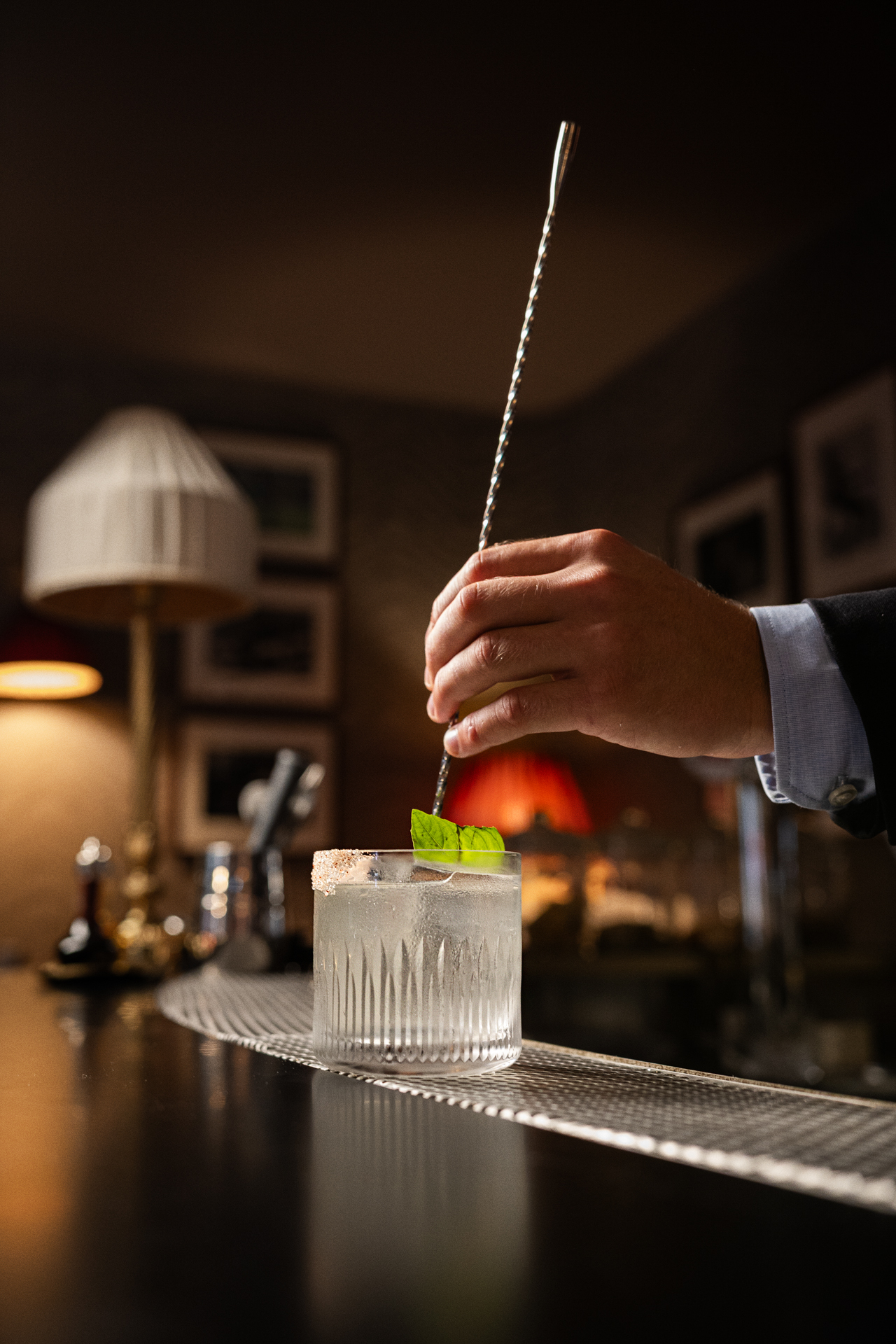 A bartender stirring a cocktail at the bar in an intimate setting