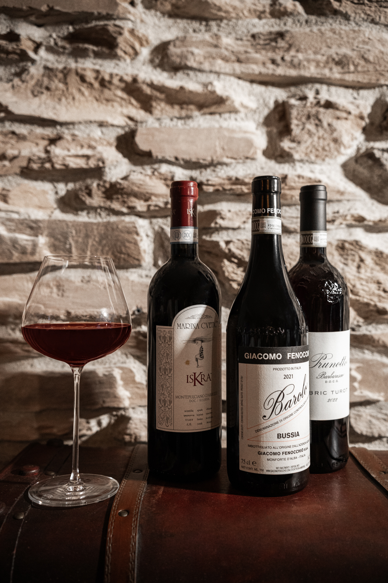 Three wine bottles and glasses in front of the cellar’s stone wall