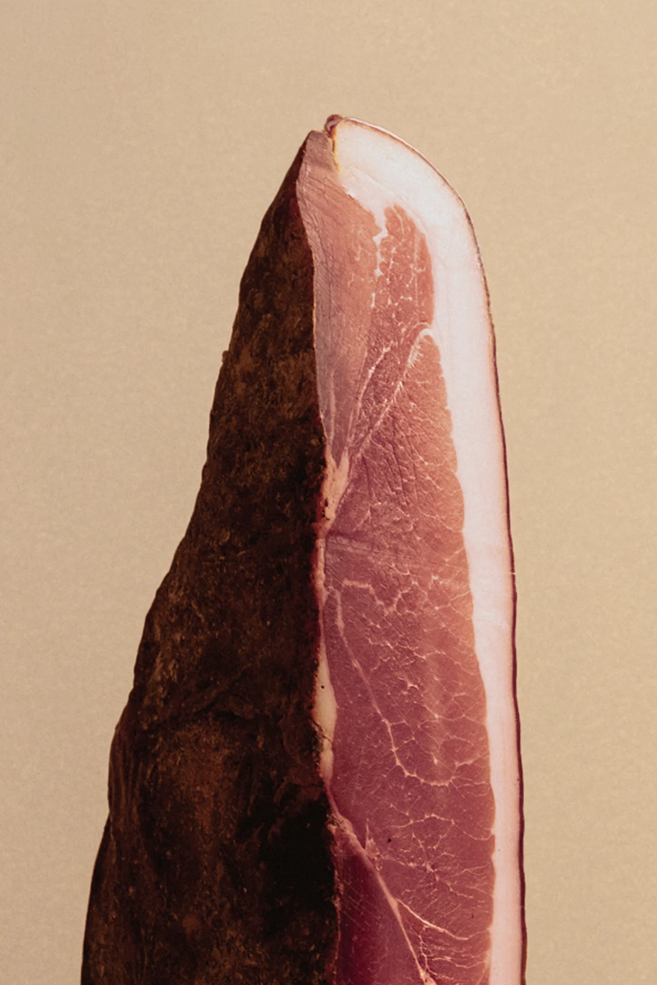 A cross-section of cured ham against a neutral backdrop