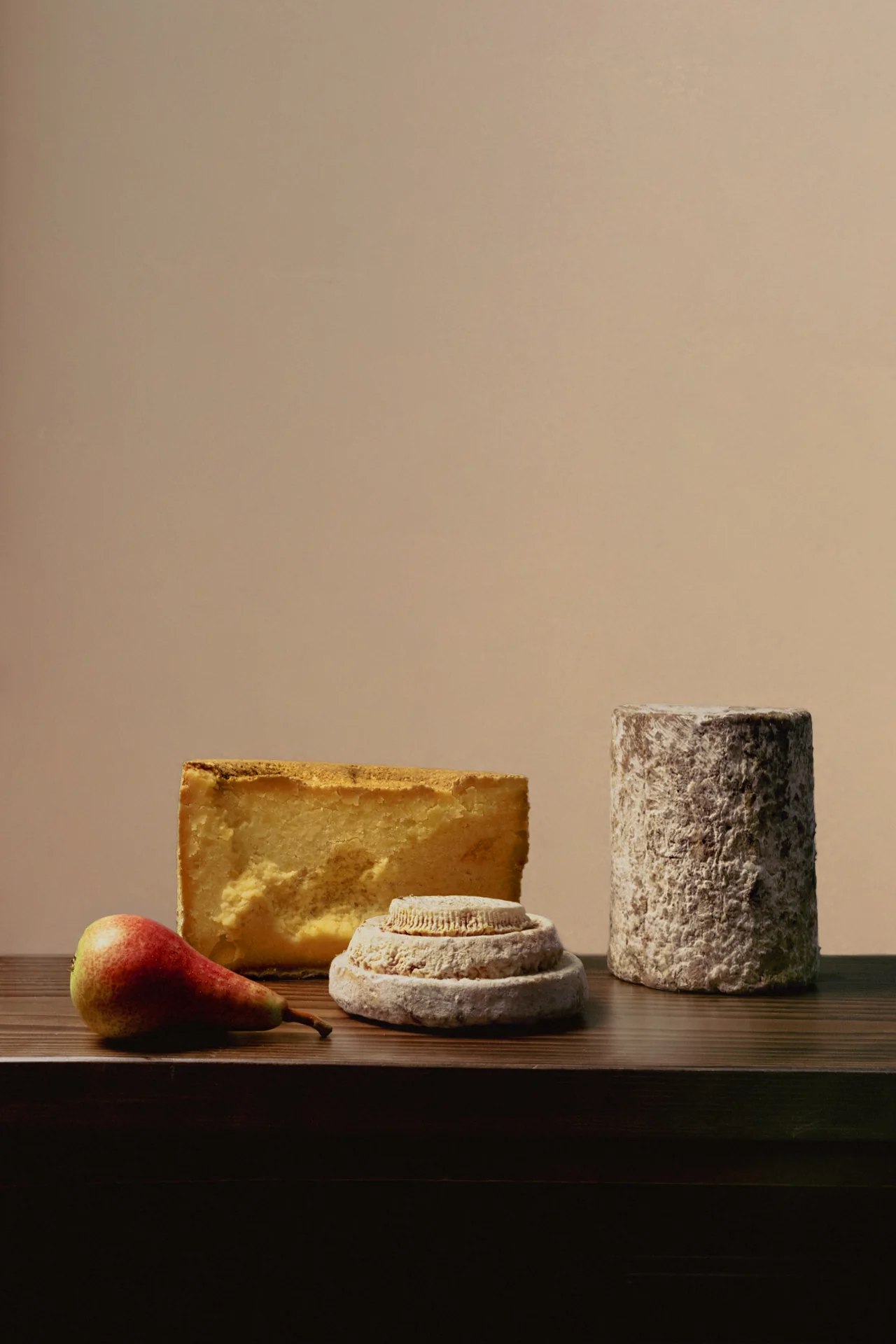 A selection of artisanal cheeses accompanied by a pear